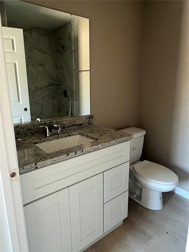 bathroom with vanity, tiled shower, and toilet