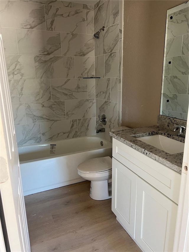 full bathroom with vanity, hardwood / wood-style flooring, toilet, and tiled shower / bath combo