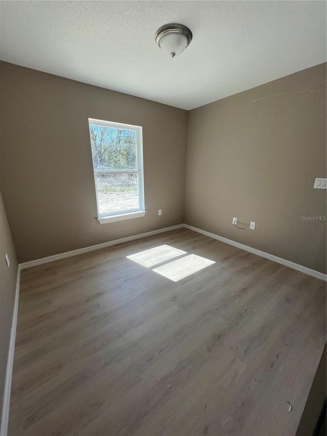 unfurnished room with hardwood / wood-style floors and a textured ceiling