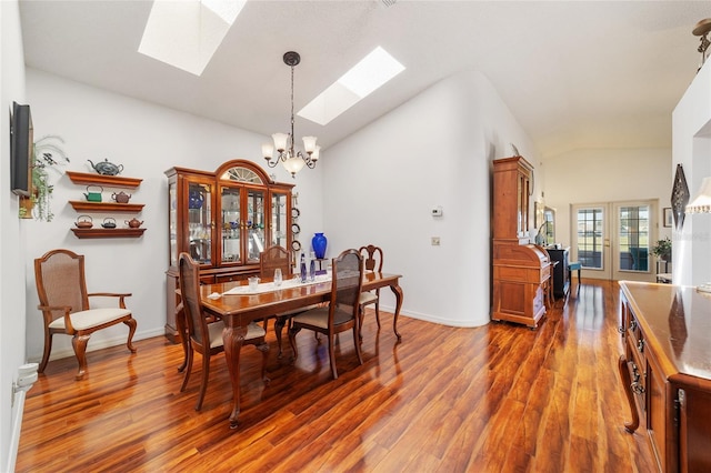 dining area with vaulted ceiling with skylight, french doors, dark wood-type flooring, and an inviting chandelier