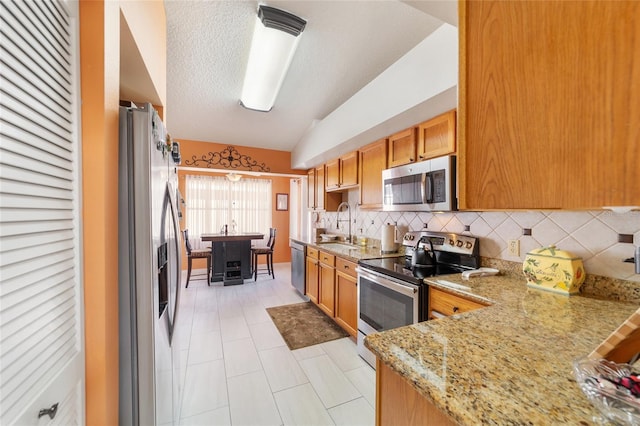 kitchen with vaulted ceiling, decorative backsplash, a textured ceiling, appliances with stainless steel finishes, and kitchen peninsula