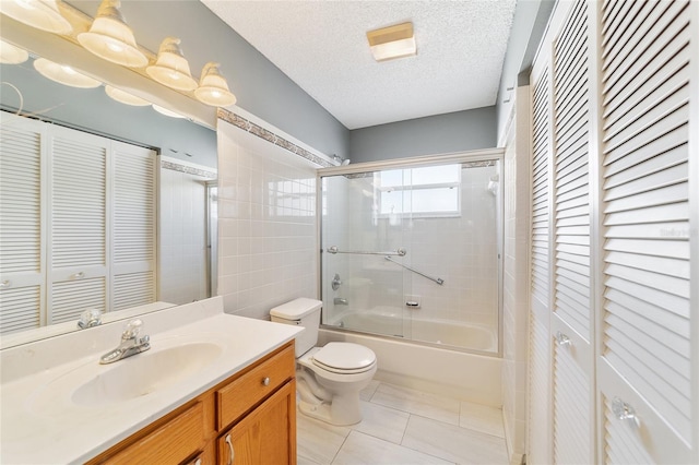 full bathroom with vanity, tile patterned floors, bath / shower combo with glass door, toilet, and a textured ceiling