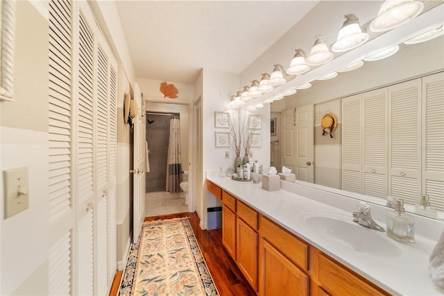 bathroom with hardwood / wood-style flooring, vanity, a textured ceiling, and toilet