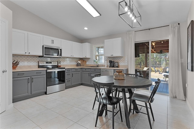 kitchen with gray cabinetry, lofted ceiling, white cabinets, sink, and stainless steel appliances