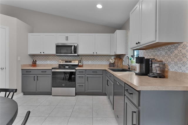 kitchen with gray cabinetry, sink, lofted ceiling, and stainless steel appliances