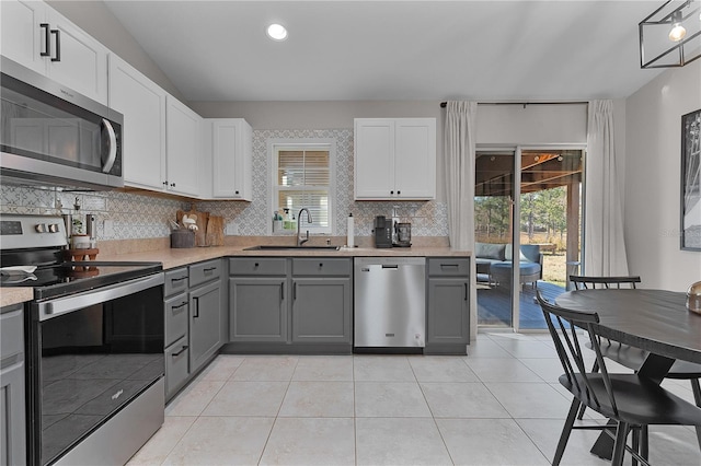 kitchen featuring gray cabinets, white cabinetry, sink, and appliances with stainless steel finishes