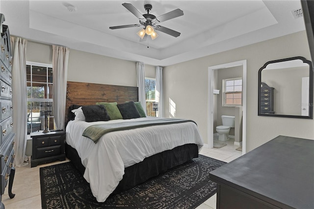 tiled bedroom with multiple windows, a raised ceiling, and ceiling fan