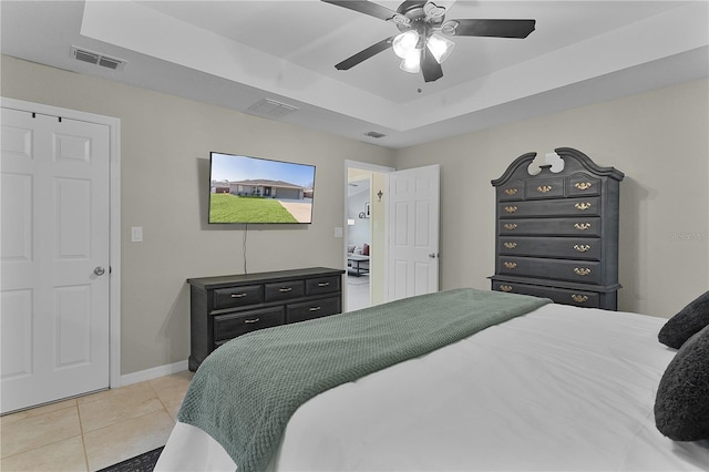 tiled bedroom with a raised ceiling and ceiling fan