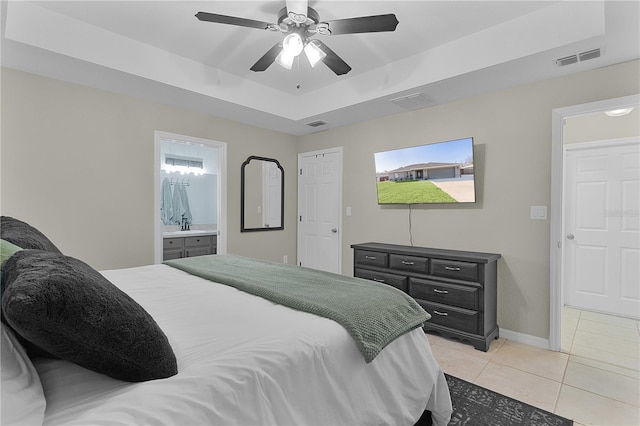 tiled bedroom with connected bathroom, a raised ceiling, and ceiling fan