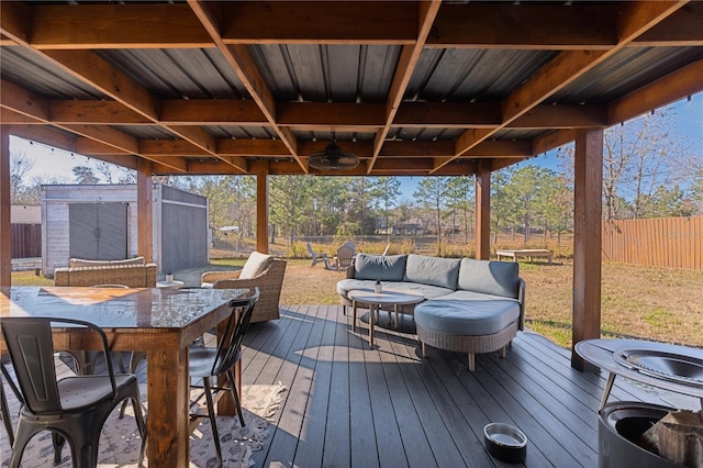 wooden deck with an outdoor hangout area, ceiling fan, and a storage shed