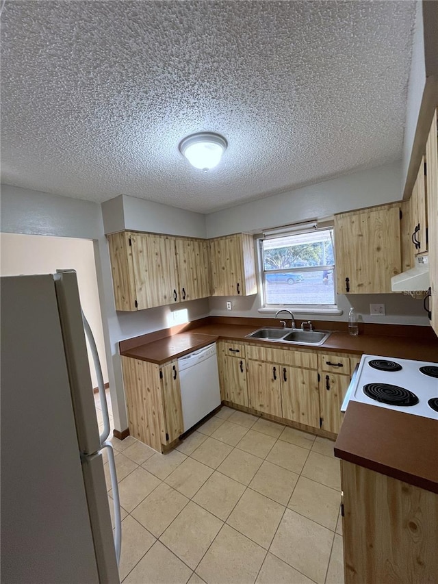 kitchen with sink, light brown cabinets, white appliances, and a textured ceiling