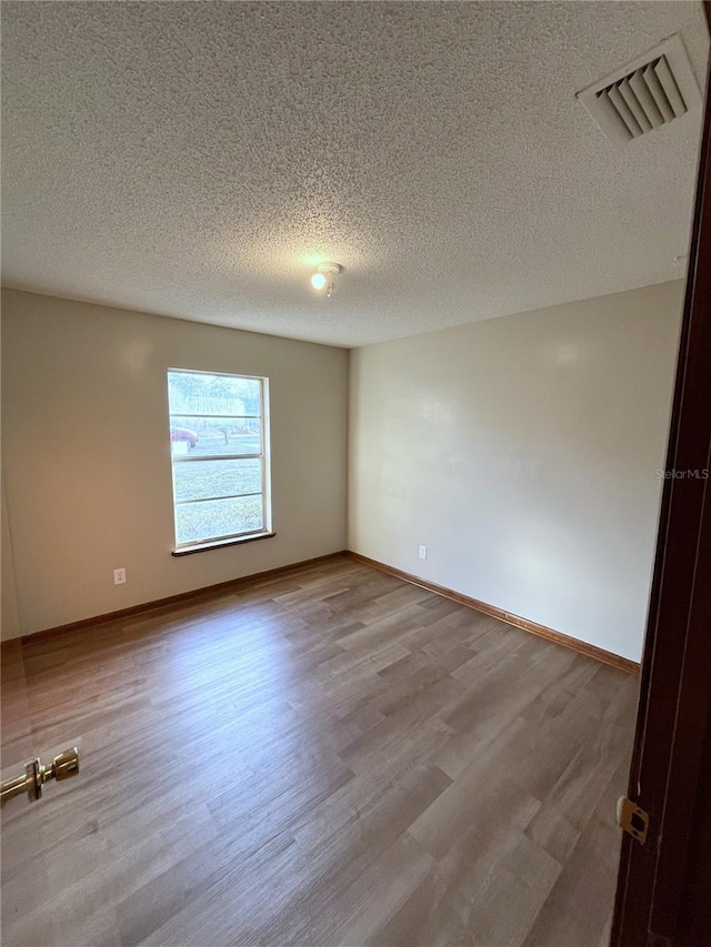 unfurnished room featuring light hardwood / wood-style flooring and a textured ceiling