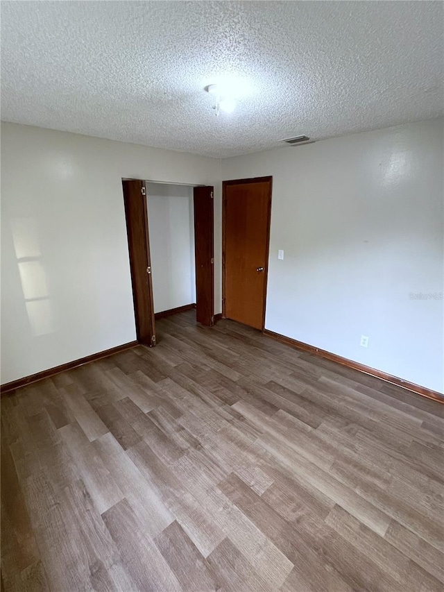 spare room featuring light hardwood / wood-style flooring and a textured ceiling