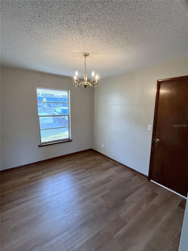 spare room featuring hardwood / wood-style floors, a textured ceiling, and a notable chandelier