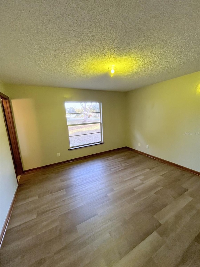 unfurnished room with light wood-type flooring and a textured ceiling