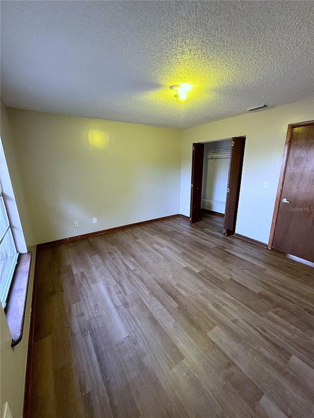 unfurnished bedroom with light hardwood / wood-style floors, a textured ceiling, and a closet