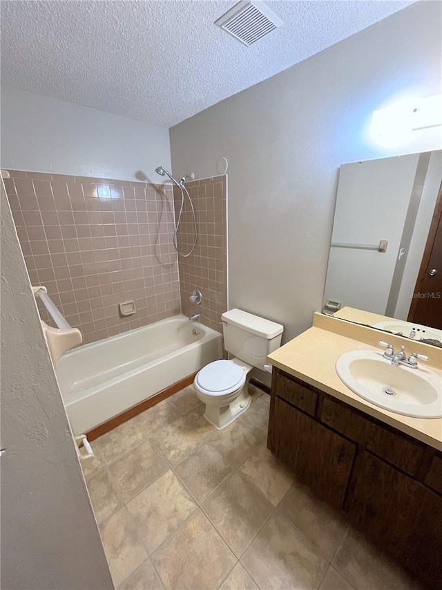 full bathroom with a textured ceiling, tiled shower / bath, tile patterned flooring, vanity, and toilet