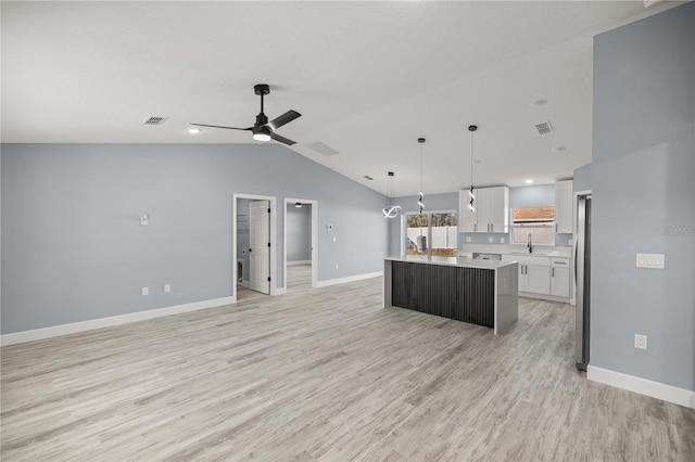 kitchen with vaulted ceiling, ceiling fan, white cabinets, a center island, and hanging light fixtures