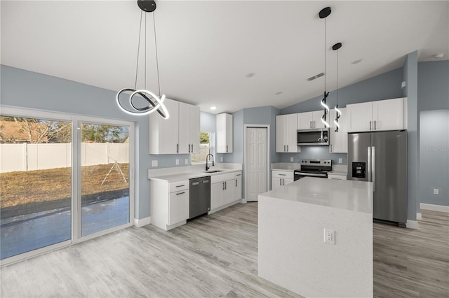 kitchen with lofted ceiling, white cabinetry, stainless steel appliances, and hanging light fixtures