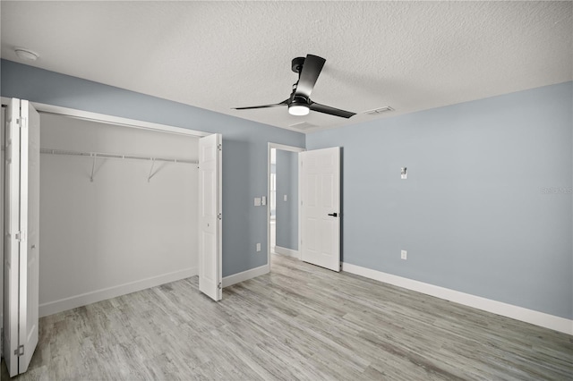 unfurnished bedroom featuring ceiling fan, a closet, a textured ceiling, and light hardwood / wood-style flooring