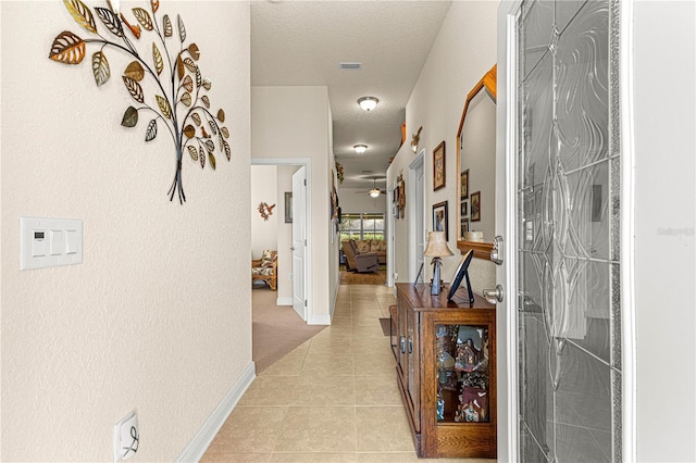 hall featuring light tile patterned floors and a textured ceiling