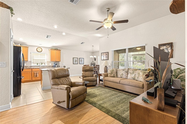 living room with light hardwood / wood-style flooring, ceiling fan with notable chandelier, a textured ceiling, and sink