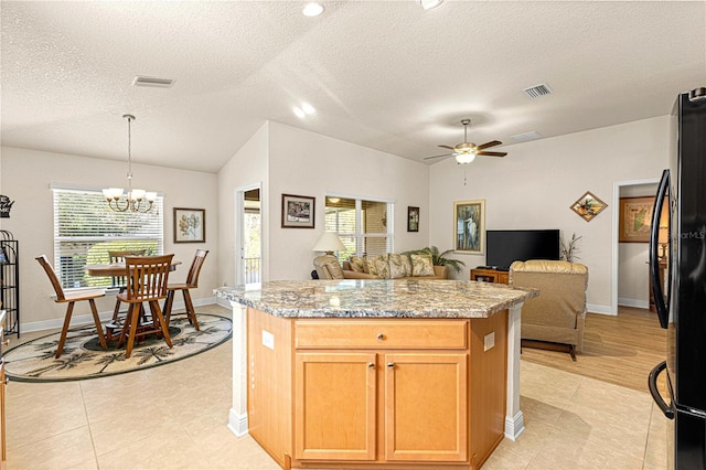 kitchen featuring pendant lighting, ceiling fan with notable chandelier, refrigerator, light stone countertops, and a textured ceiling