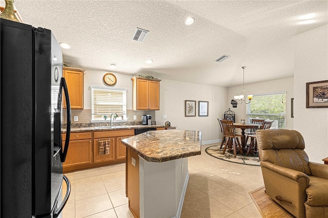 kitchen featuring sink, a center island, black appliances, and light tile patterned floors