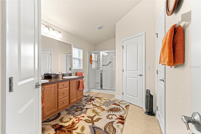 bathroom featuring vanity, a textured ceiling, vaulted ceiling, a shower with door, and tile patterned flooring