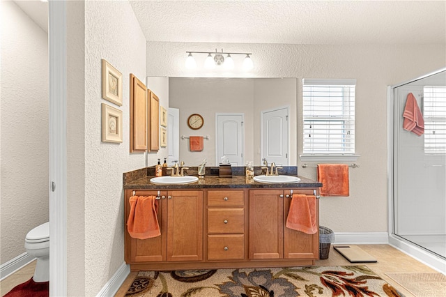 bathroom with a textured ceiling, vanity, toilet, and an enclosed shower