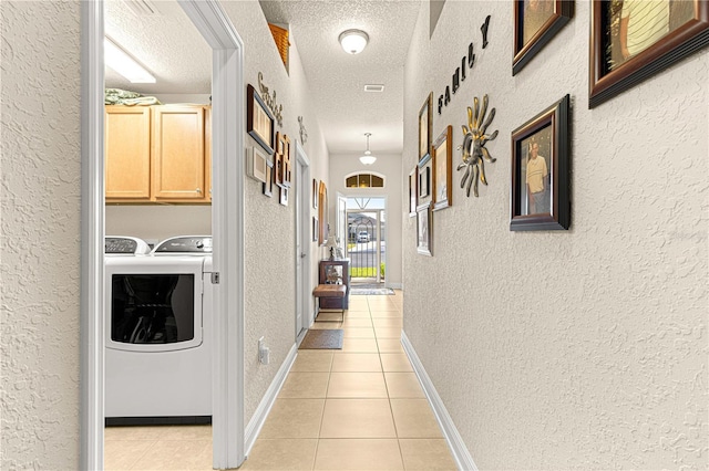 hall with independent washer and dryer, light tile patterned floors, and a textured ceiling