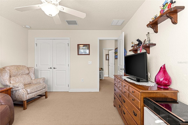 interior space featuring a textured ceiling, ceiling fan, light carpet, and a closet