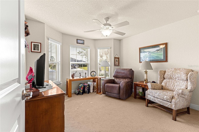 sitting room featuring a textured ceiling, ceiling fan, and light carpet