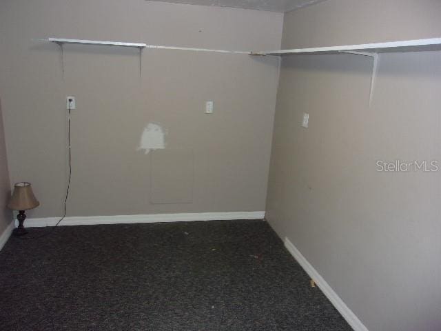 walk in closet with dark carpet