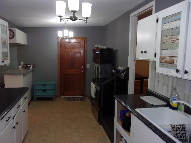 kitchen with white cabinets, an inviting chandelier, hanging light fixtures, and sink