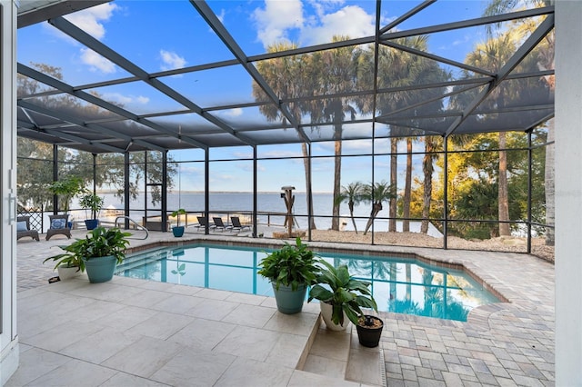 view of swimming pool featuring a lanai, a patio, and a water view