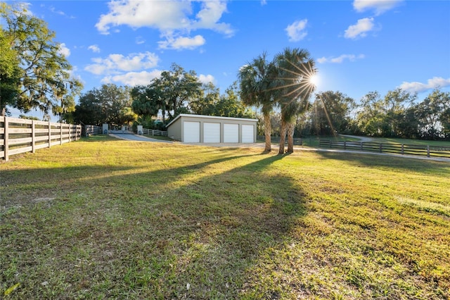 view of yard featuring a rural view, a garage, and an outdoor structure