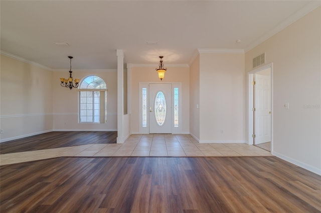 foyer entrance with hardwood / wood-style floors, ornamental molding, and a chandelier