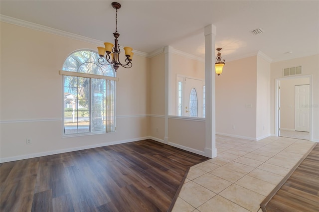 spare room featuring hardwood / wood-style flooring, ornamental molding, and an inviting chandelier