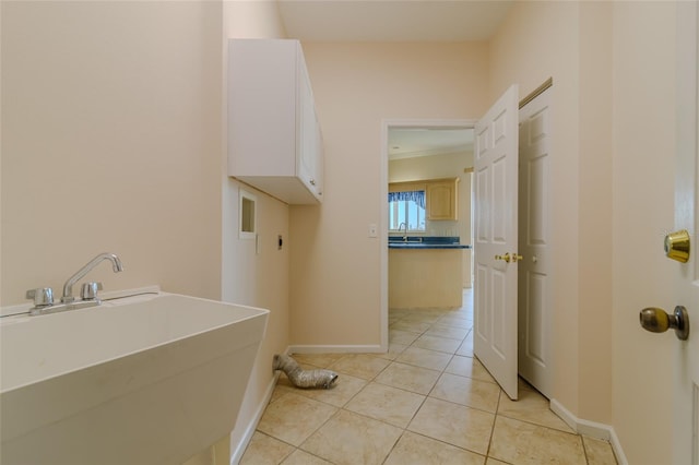 laundry area with light tile patterned flooring, cabinets, and sink