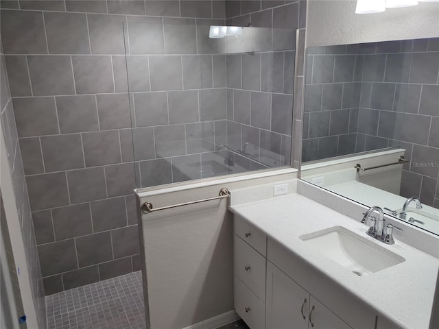 bathroom with a tile shower and vanity