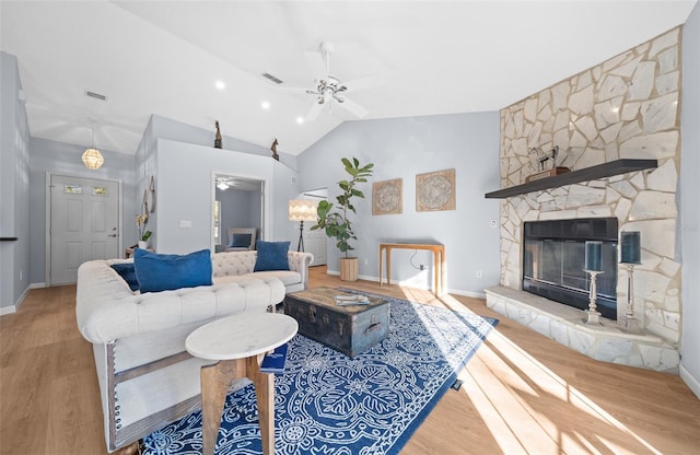 living room featuring ceiling fan, lofted ceiling, a fireplace, and light hardwood / wood-style flooring