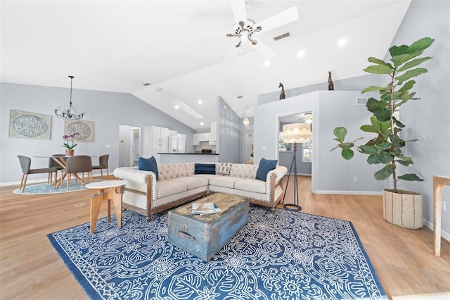 living room with ceiling fan with notable chandelier, light hardwood / wood-style floors, and high vaulted ceiling