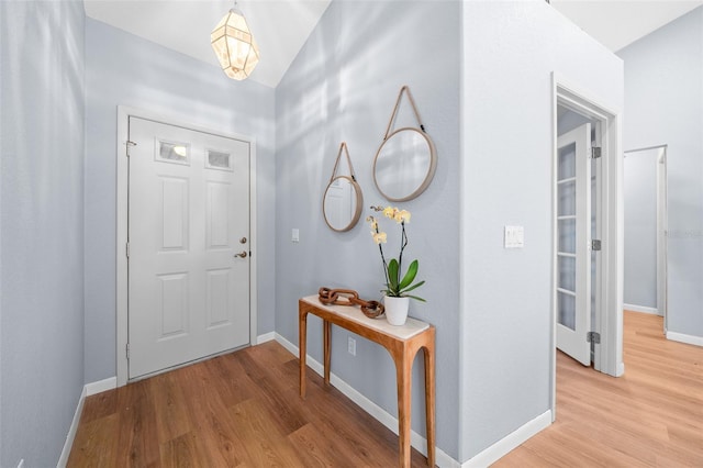 foyer entrance with hardwood / wood-style floors and vaulted ceiling