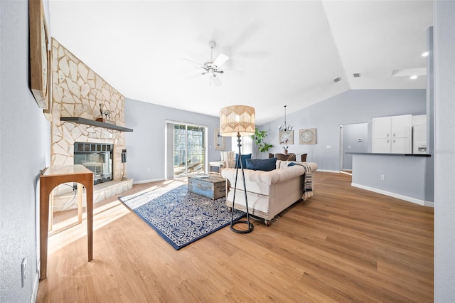 living room with hardwood / wood-style floors, ceiling fan, a fireplace, and vaulted ceiling