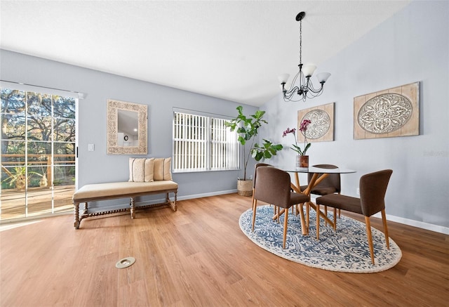 dining area featuring hardwood / wood-style flooring, lofted ceiling, and an inviting chandelier