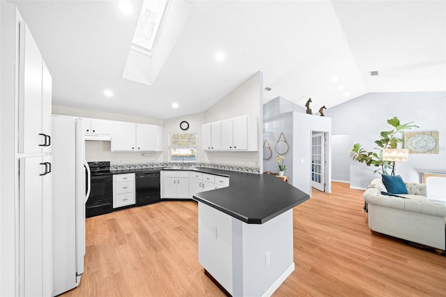 kitchen featuring kitchen peninsula, vaulted ceiling with skylight, white cabinets, black appliances, and light wood-type flooring