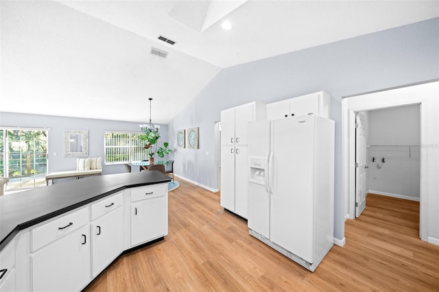 kitchen with white fridge with ice dispenser, white cabinets, pendant lighting, and lofted ceiling