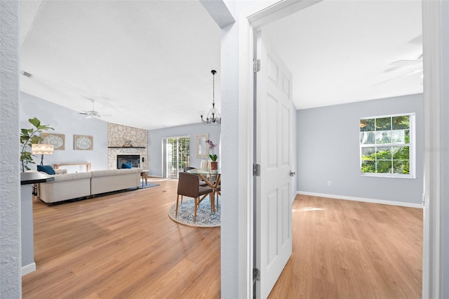 hall featuring vaulted ceiling, light hardwood / wood-style flooring, and an inviting chandelier