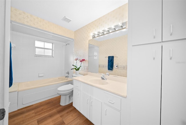 full bathroom with vanity, hardwood / wood-style flooring, toilet, and tiled shower / bath